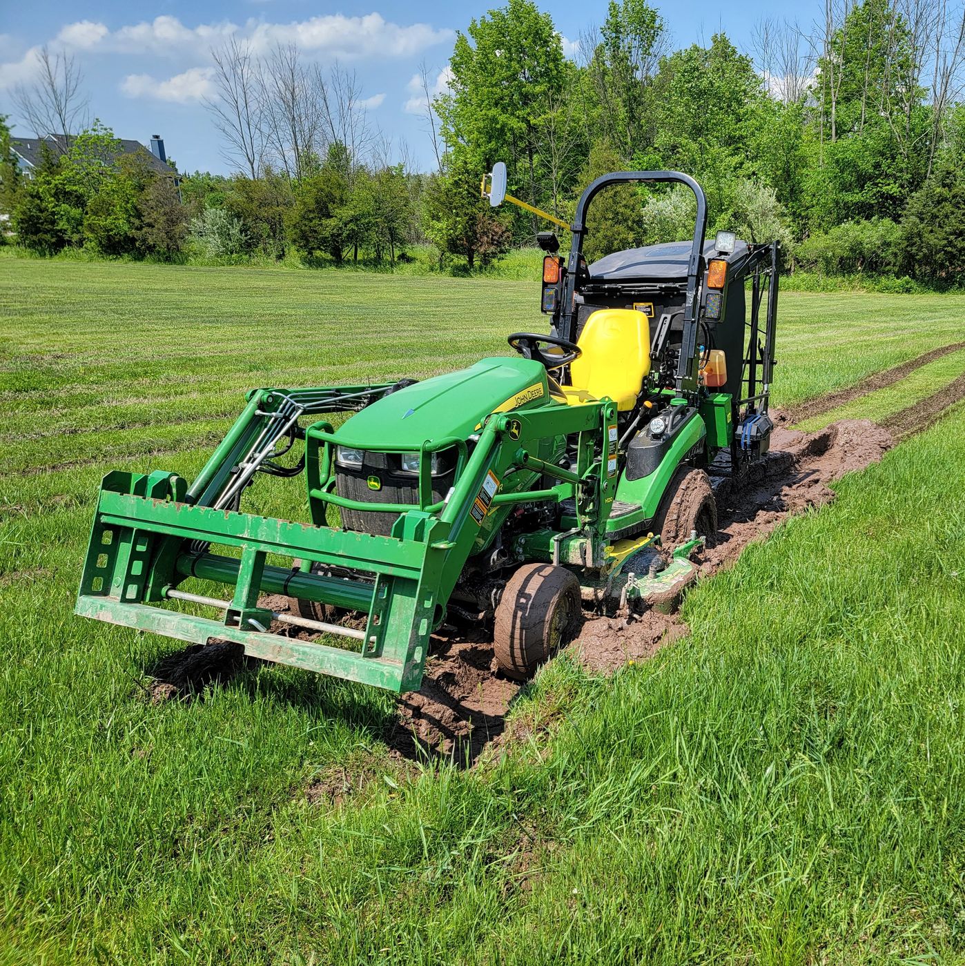 Compact tractor running a loader out in the field