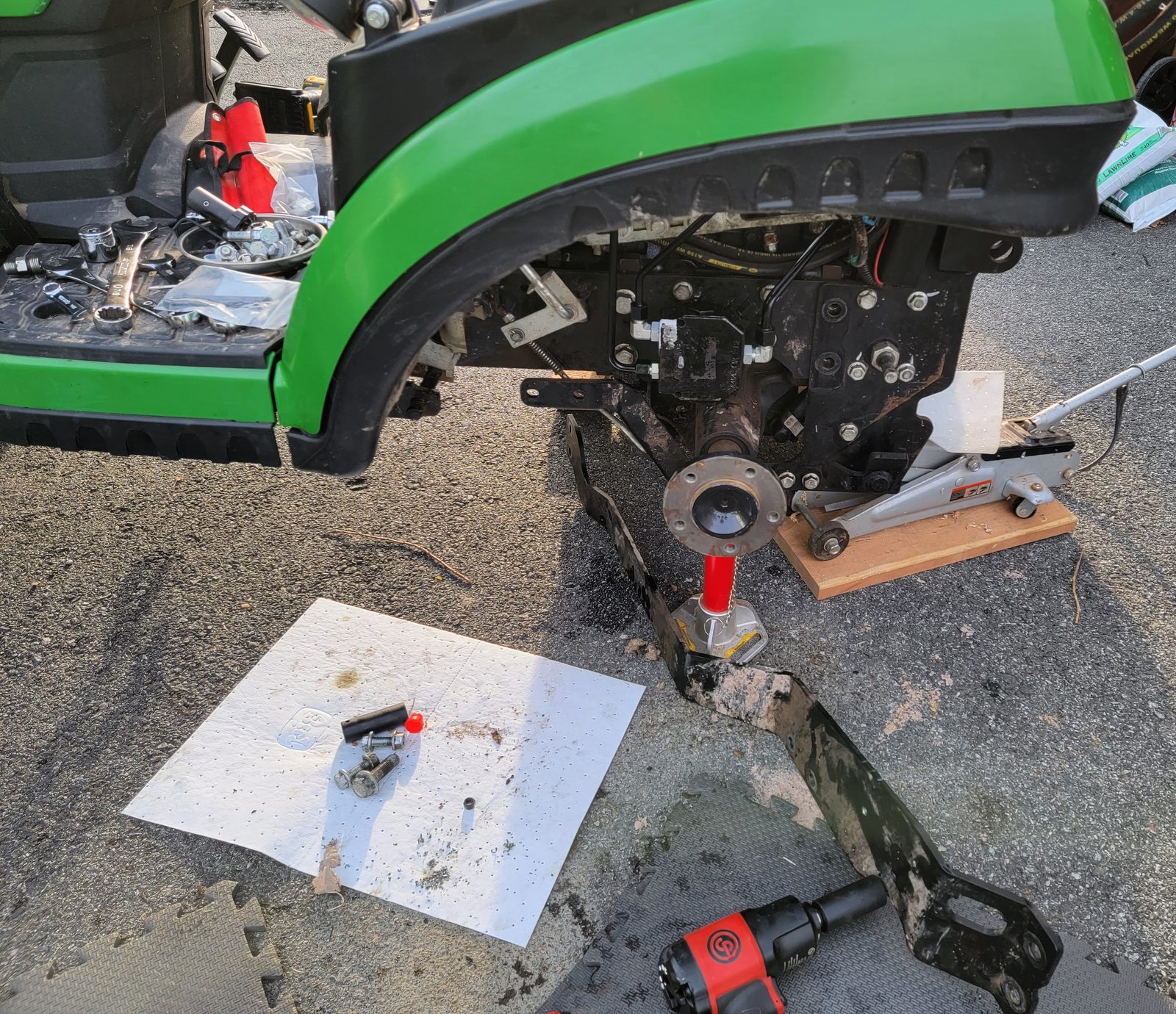 Compact tractor up on a jack with a wheel removed for axle service